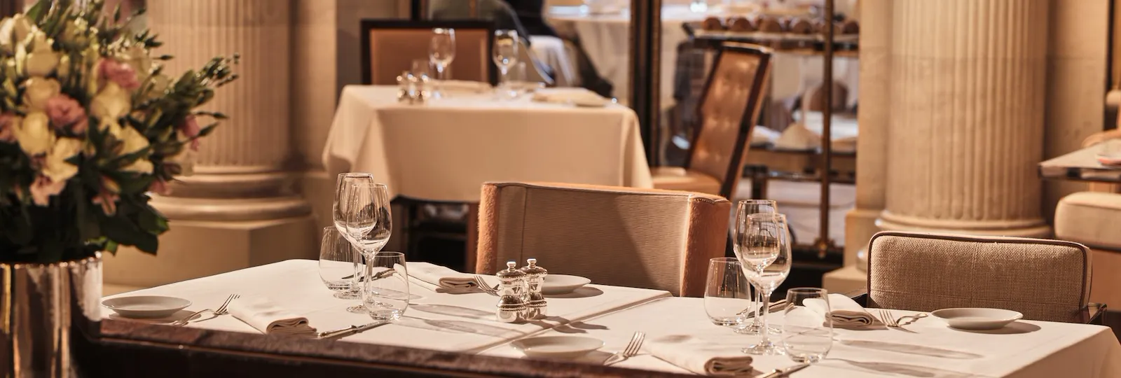 Elegant restaurant with set tables, floral decor, candles, and relaxed dining ambiance