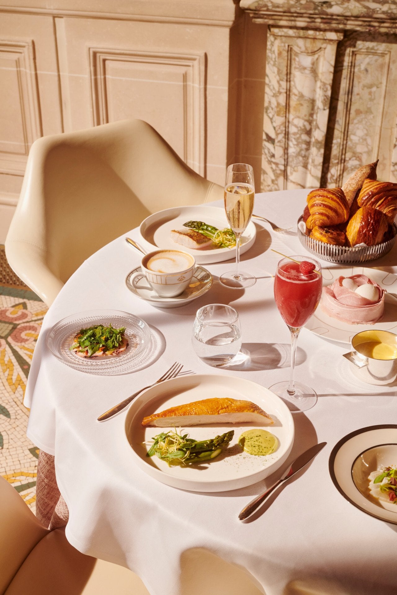 Vista superior de uma mesa de brunch com peito de frango com uma taça de champanhe, coquetel e uma xícara de café no Le Meurice, Paris - Coleção Dorchester