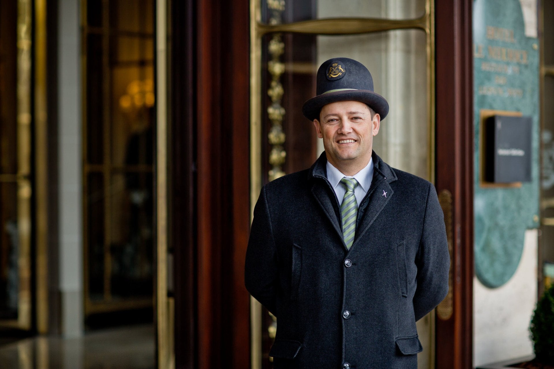 Cette photo représente un voiturier souriant devant la porte principale du Meurice, Paris