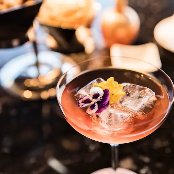 Coppa di cocktail La Grande Bellezza appoggiata su di un tavolo a Il Giardino bar