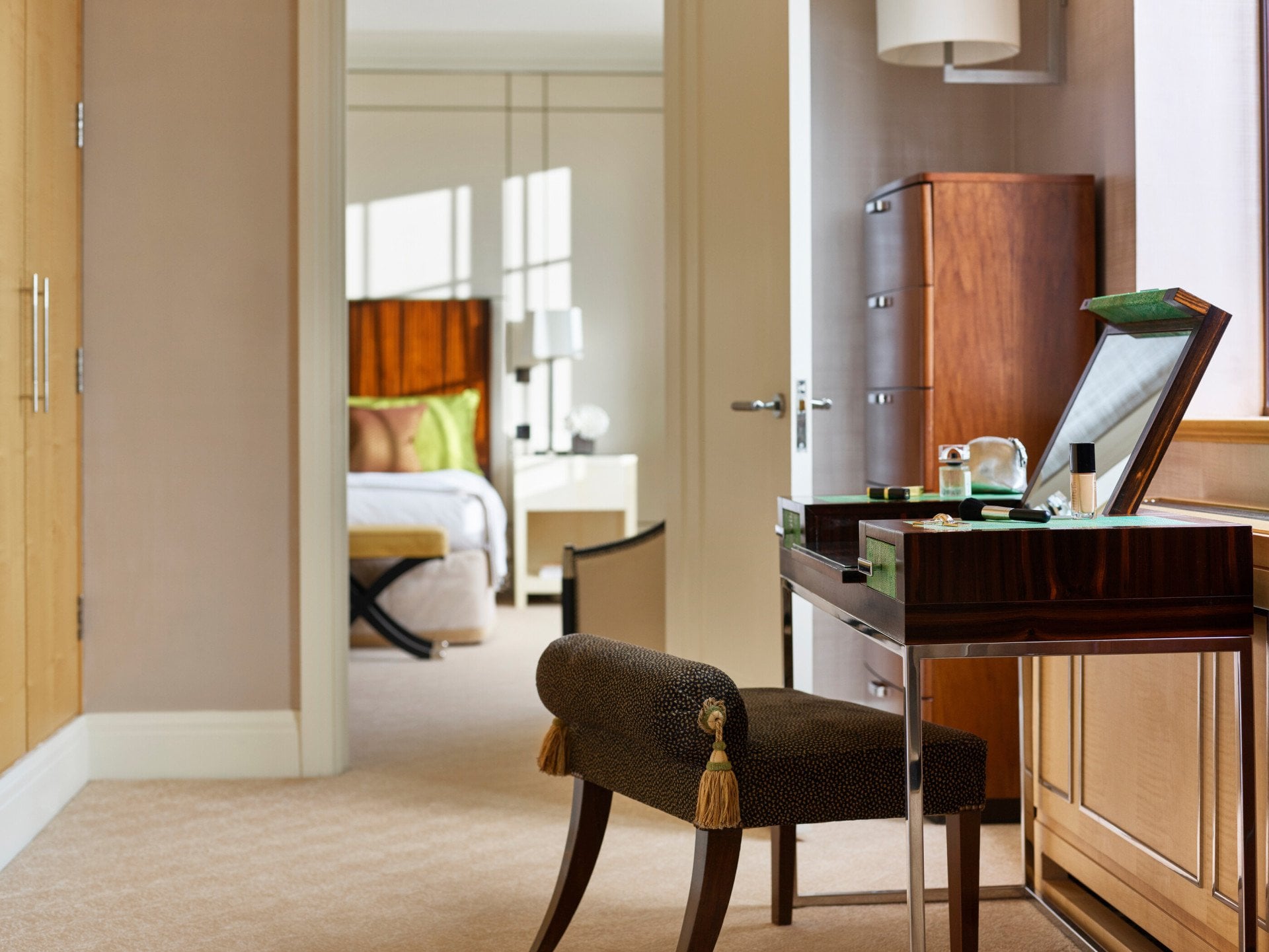 The Harlequin Penthouse Suite vanity table with make up on display and bedroom in background