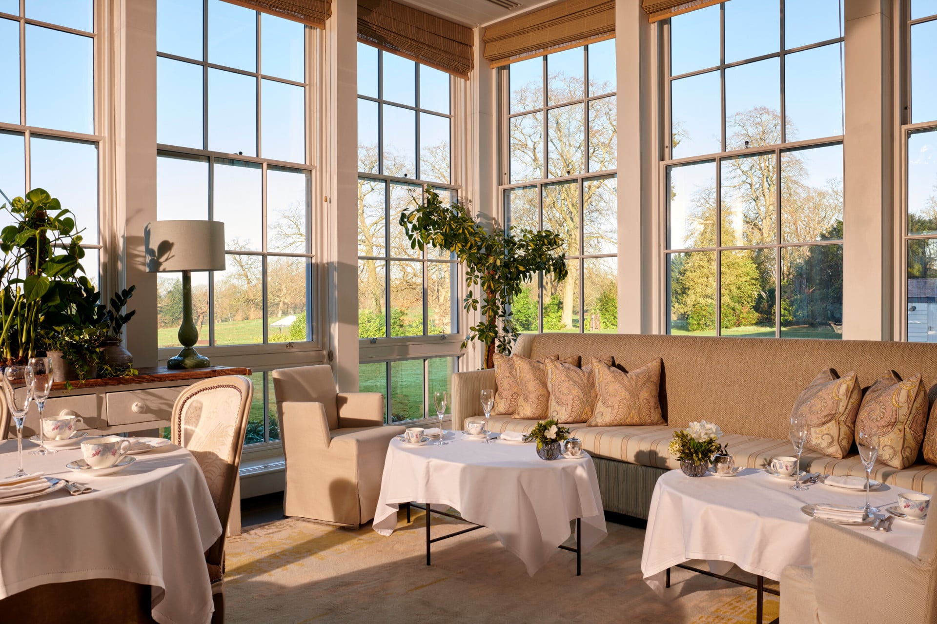 Coworth Park Drawing Room conservatory with champagne and cakes on table 