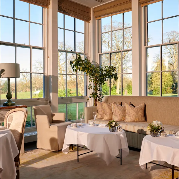 Coworth Park Drawing Room conservatory with champagne and cakes on table