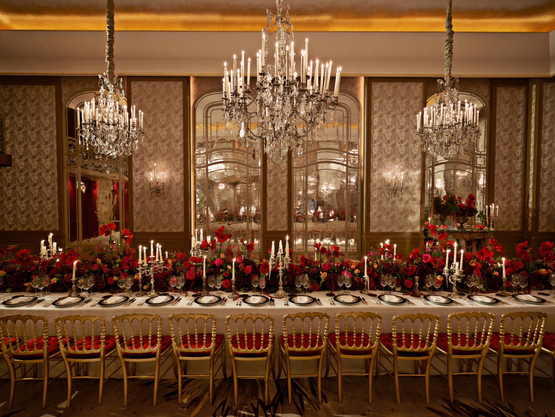 Jantar com uma mesa comprida e flores vermelhas captado no Salon Haute Couture, no Hôtel Plaza Athénée, Paris - Dorchester Collection.