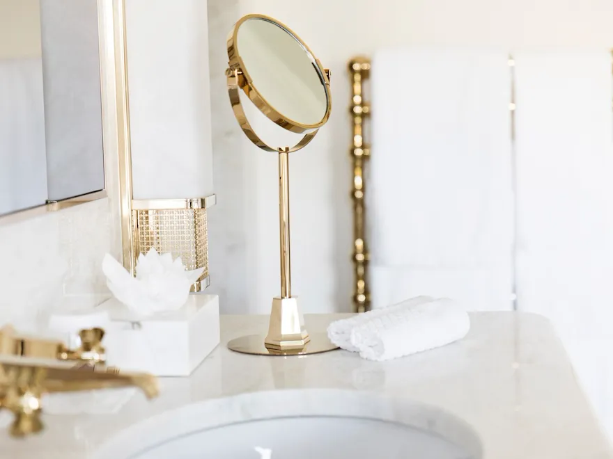 Bathroom detail with vanity mirror, towels and white marble sink at Hotel Eden, Rome