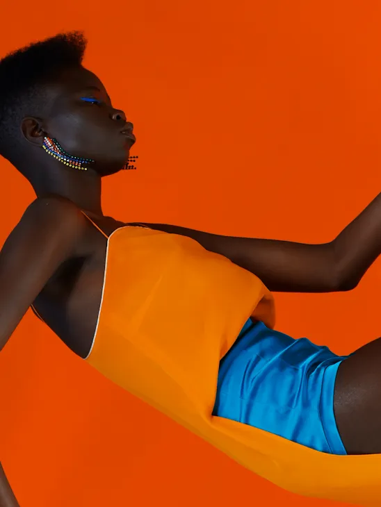 One of photographer Zach Gold's works depicting a woman wearing an orange top and electric blue shorts against an orange background.