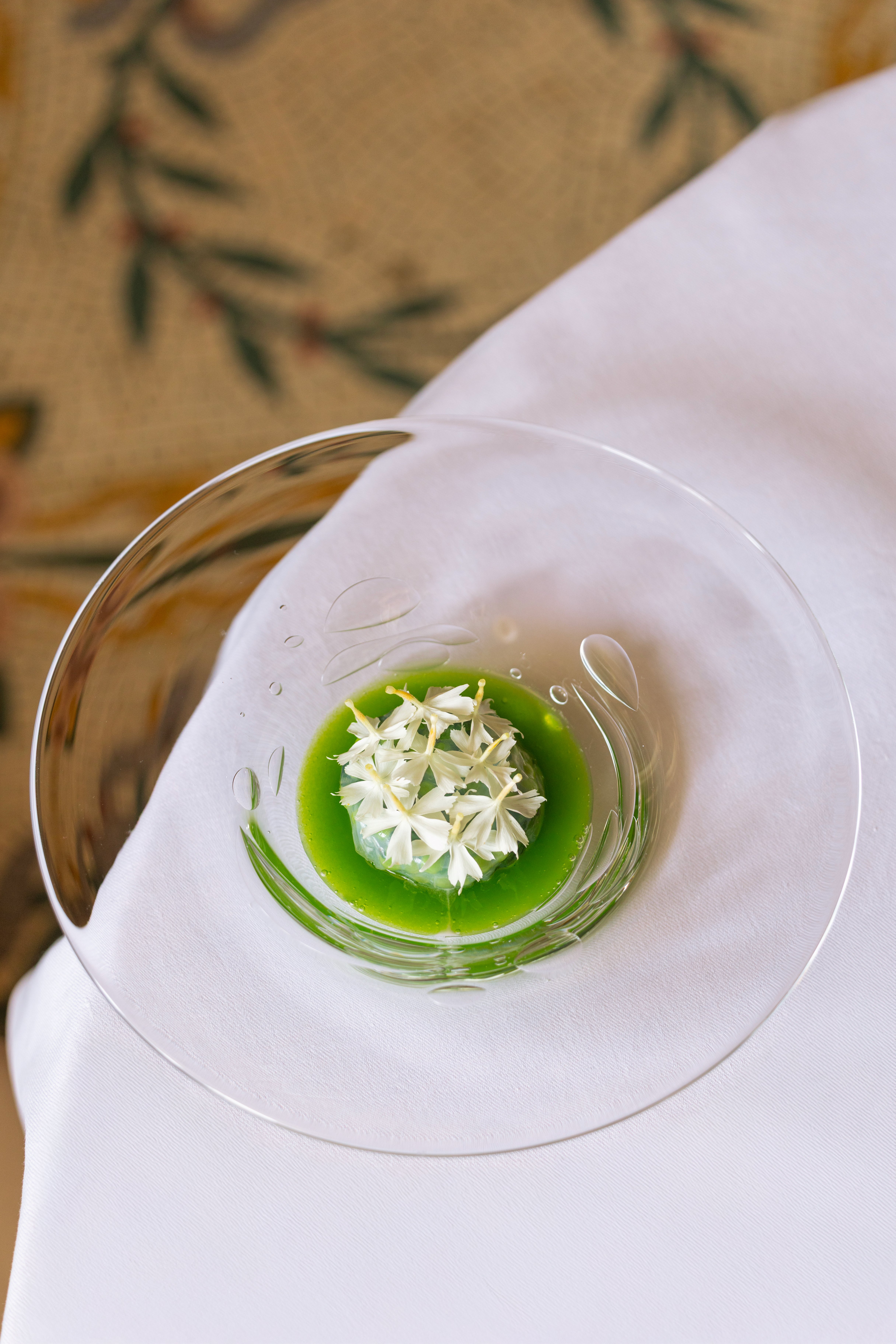 Spider crab, pees and flowers in a transparent plate served at Le Meurice Alain Ducasse.