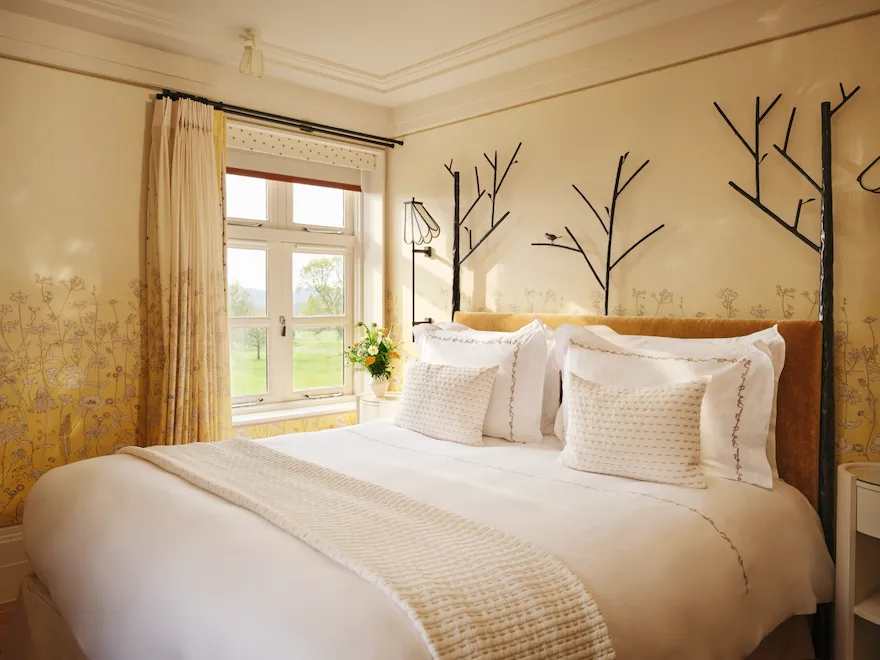 Bedroom with nature-inspired four-poster bed and garden views in the Gardeners suite at Coworth Park, Ascot