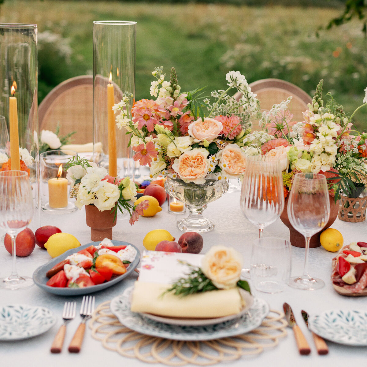 Outdoor garden table set for a social event with floral centrepieces and seasonal fruit at Coworth Park, Ascot