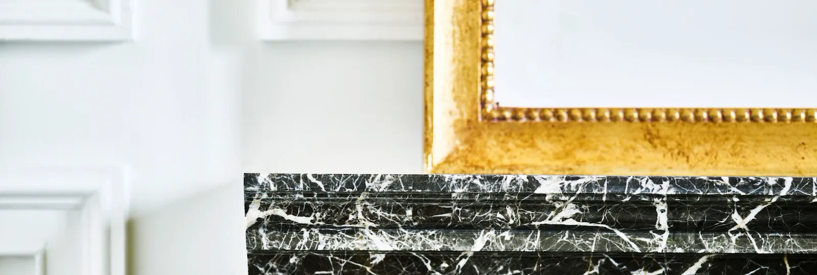 Detail of black marble with white veins shelf and mirror with golden frame at Hotel Eden, Rome