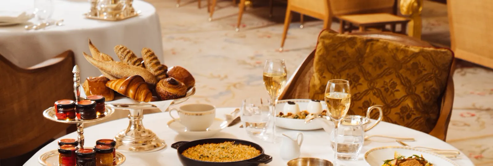 Elegant banquet table set for dining with food, drinks, and desserts in a formal setting