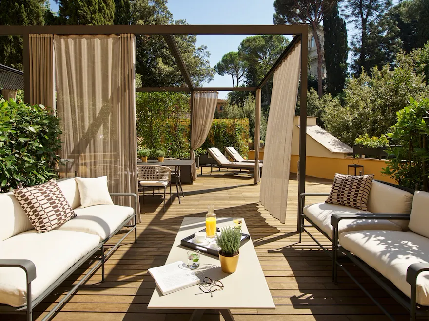 Outdoor patio with sofas, curtains, and sunshine creating a relaxing, peaceful atmosphere