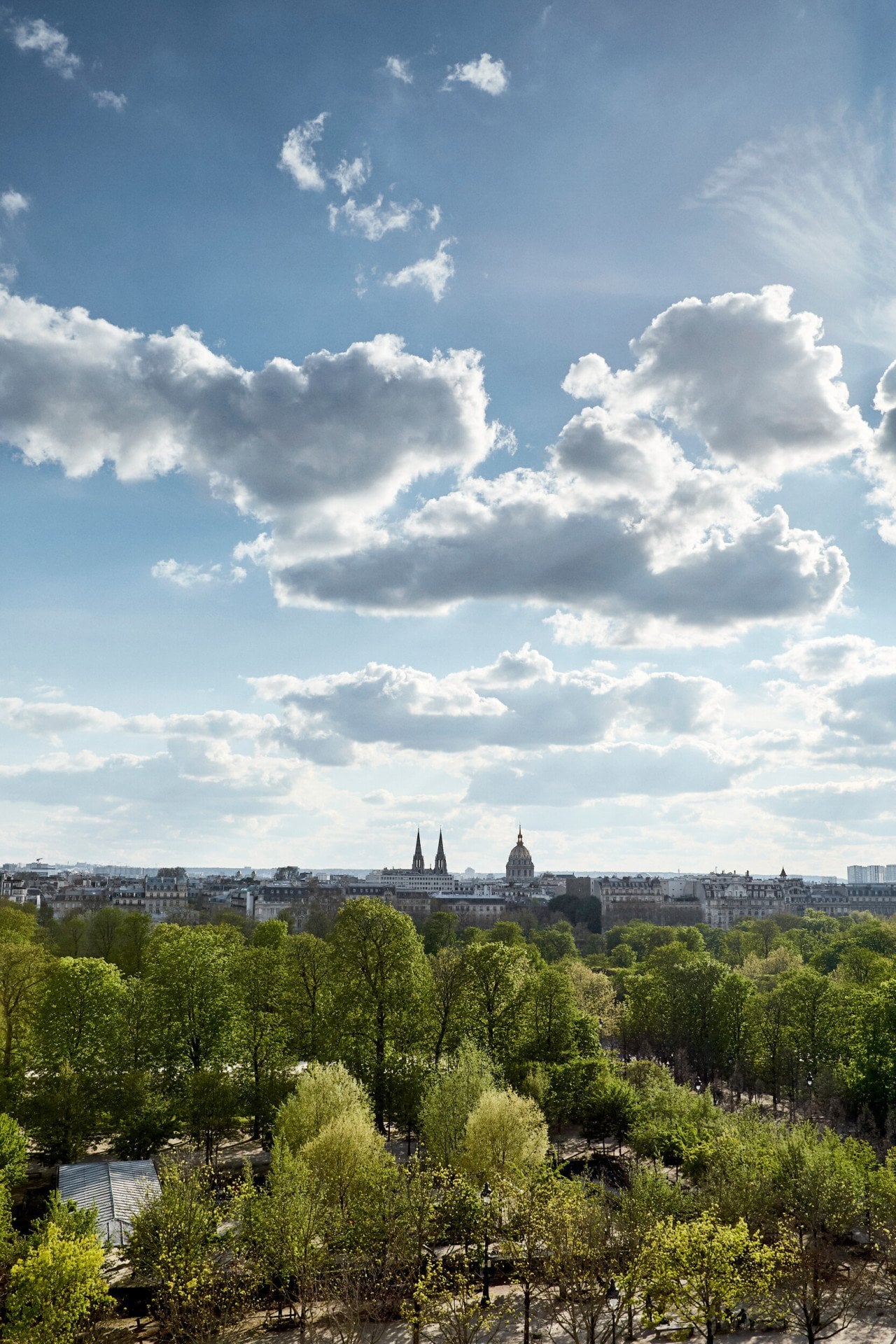 Vista de um quarto executivo do lado do parque, com o Jardim das Tulherias e a cidade ao fundo. No Le Meurice, Paris.