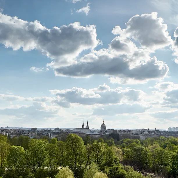 Vista de um quarto executivo do lado do parque, com o Jardim das Tulherias e a cidade ao fundo. No Le Meurice, Paris.